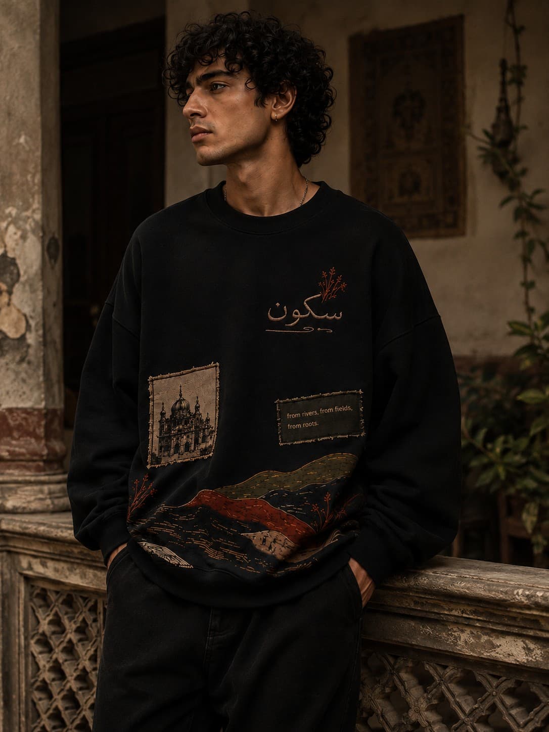 Man wearing the Sakoon black crewneck, front view, embroidered سکون at the chest